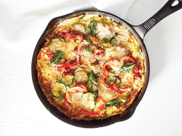 Cast iron baked ham frittata with fresh veggies and garnished with basil