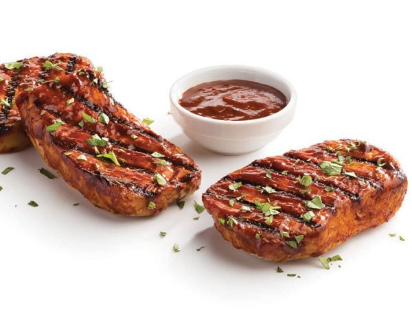 Grilled hot spicy pork chops with sauce and garnished with fresh parsley