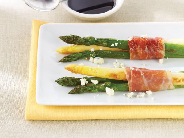 White and green asparagus wrapped with prosciutto and garnished with crumbled cheese