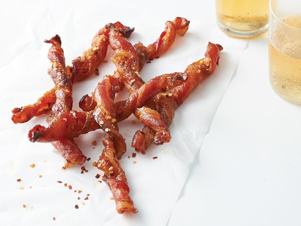 Bacon spirals on parchment paper sprinkled with red pepper flakes