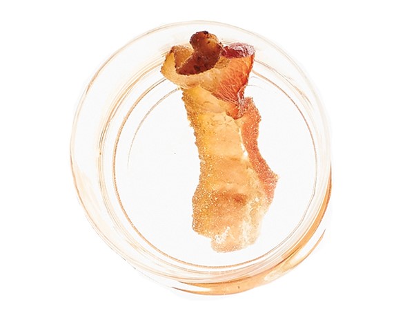 Glass of bacon-infused tequila with a slice of bacon