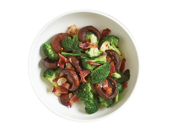 Bowl of broccoli, bacon and mushrooms sprinkled with red pepper flakes