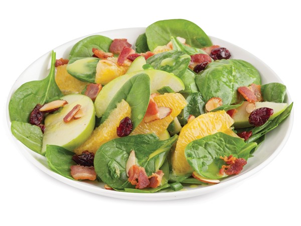 Plate of spinach topped with bacon, cranberries, green onions, apple slices, orange slices and sliced almonds