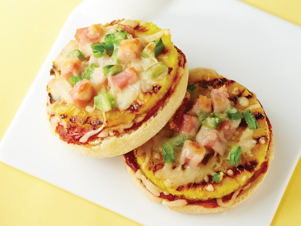 Mini pizzas on English muffins with grilled pineapple and topped with cheese, meat, and veggies