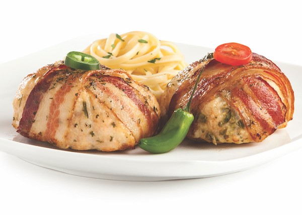Plate of two bacon-wrapped chicken grillers, one garnished with a jalapeno, the other with a grape tomato