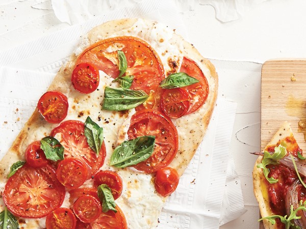 Pizza topped with fresh tomato slices and basil