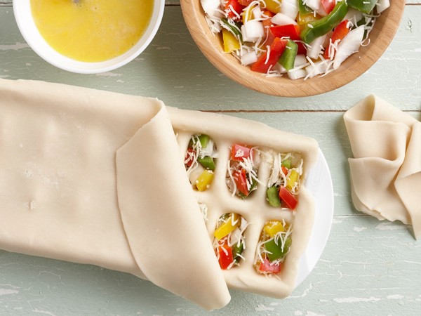 Pizza rolls with pie dough, vegetables, and cheese in ice cube tray