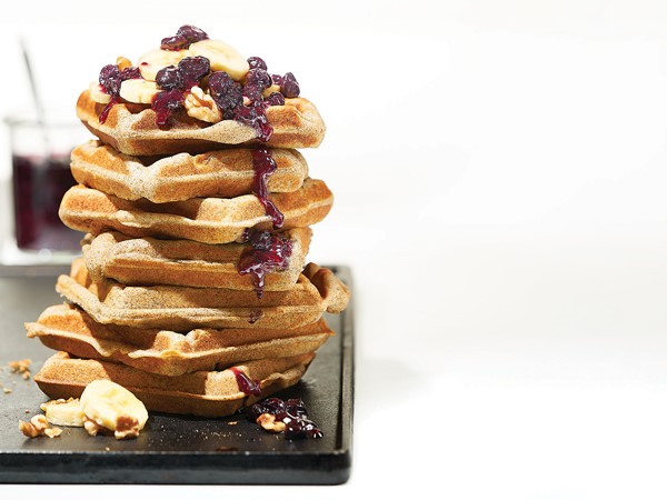 Stack of banana buckwheat waffles topped with banana slices, walnuts and blueberry-chia syrup