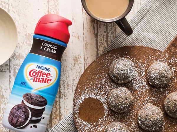 Round platter of cookies and cream donut holes sprinkled in powdered sugar next to cookes and cream Coffeemate