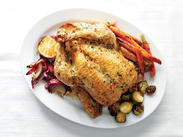 Whole roasted chickens on top of roasted vegetables