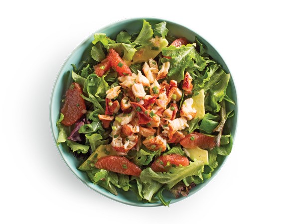 Shredded lobster and citrus wedges on top of salad greens