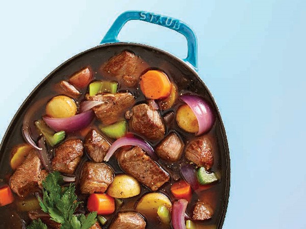 Beef stew with stewed vegetables and fresh parsley in Dutch oven
