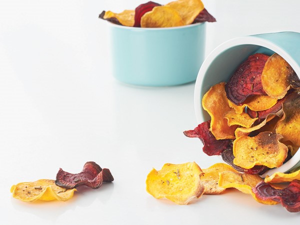 Sweet potato and beet chips spilling out of blue containers