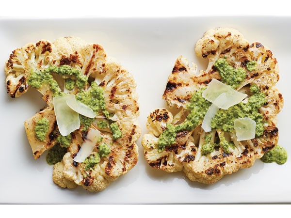 Grilled cauliflower steaks topped with salsa verde and parmesan shavings