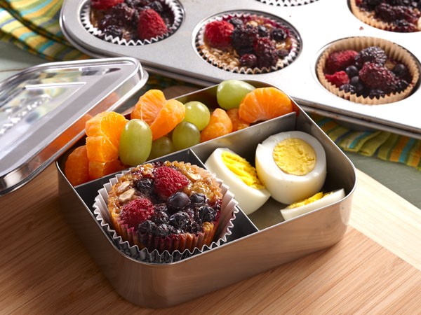 Aluminum container with compartments filled with a baked oatmeal cup, hard boiled eggs and fruit