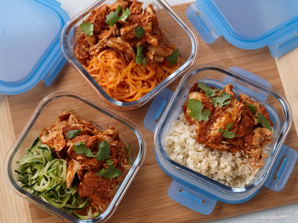 Glass containers filled with chicken tinga and sides of rice, zucchini or carrots