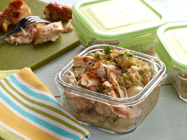 Mashed veggies topped with shredded chicken in glass container