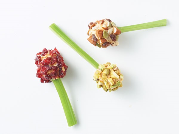 Seedless grapes covered in almond butter and dried fruit and nuts and attached to celery sticks