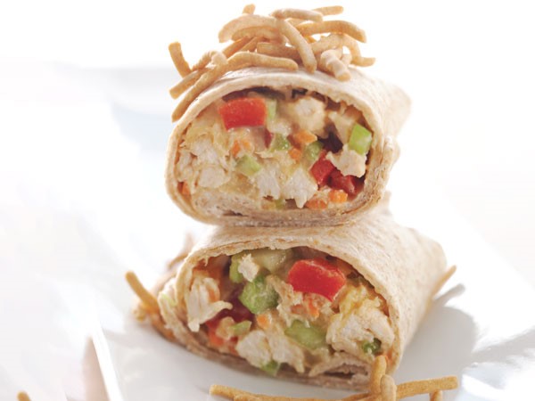 Asian chicken salad wraps stacked on parchment paper
