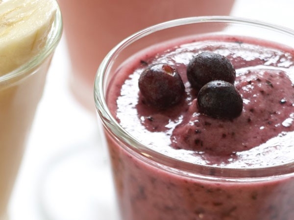 Glass filled with blueberry blast smoothie and topped with fresh blueberries