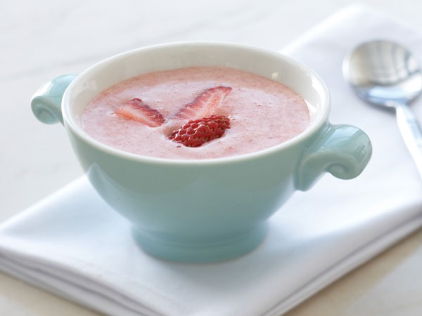 Bowl of pink chilled strawberry soup garnished with strawberry slices