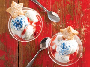 Red wood background with glasses of gelato with blue sprinkles and star cookies