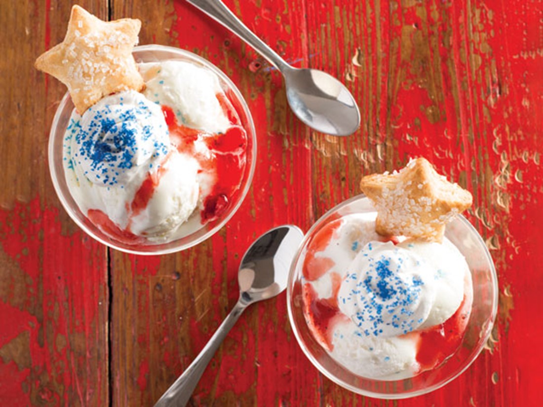 Red wood background with glasses of gelato with blue sprinkles and star cookies