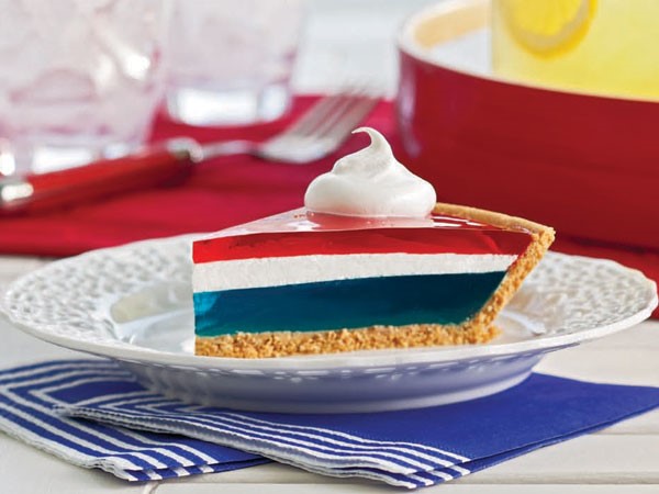Red, white, and blue jello pie with graham cracker crust on white plate