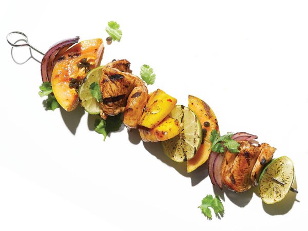 Grilled chicken, papaya, mango, and red onion on a metal skewer
