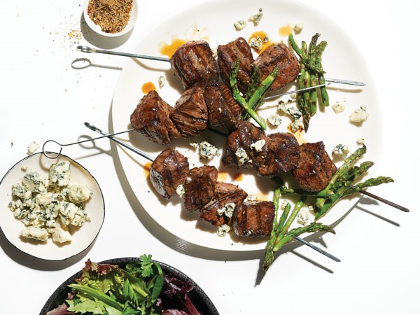 Beef skewered with asparagus on white plate