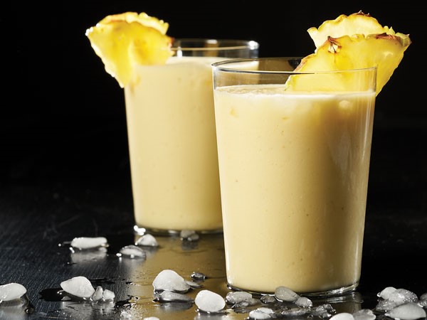 To glasses of pineapple ginger smoothie topped with pineapple wedge