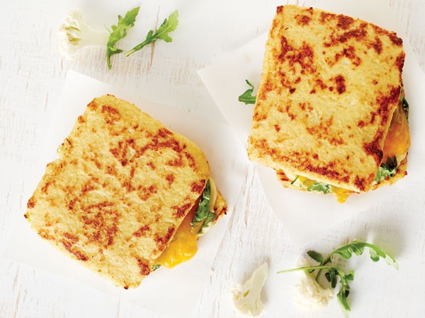 Two cauliflower grilled cheese sandwiches on white background