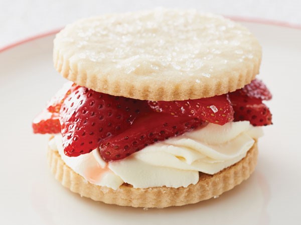 Shortbread cookies sandwiching frosting and fresh strawberry slices