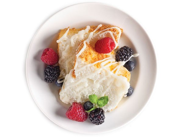 Plate of angel food cake topped with drizzled icing and fresh berries