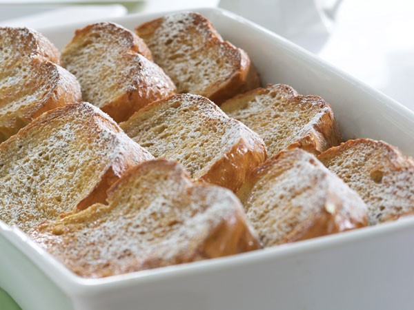 Casserole dish of baked french toast topped with powdered sugar