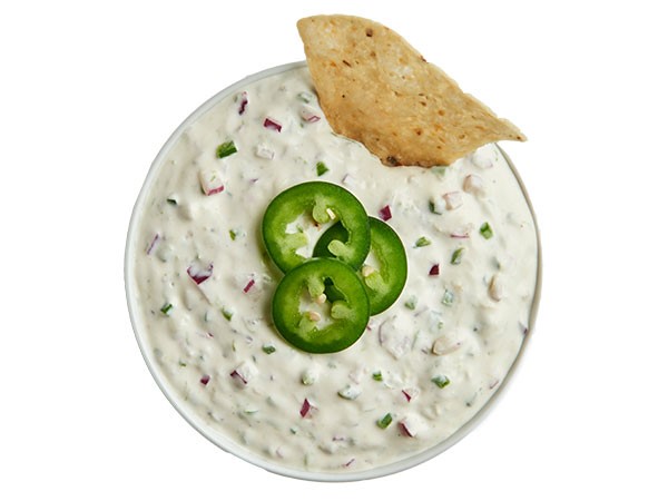 Cilantro lime dip garnished with fresh jalapeno slices and chip