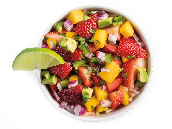 Strawberry avocado pico de gallo with fresh fruit and veggies in a white bowl with lime wedge