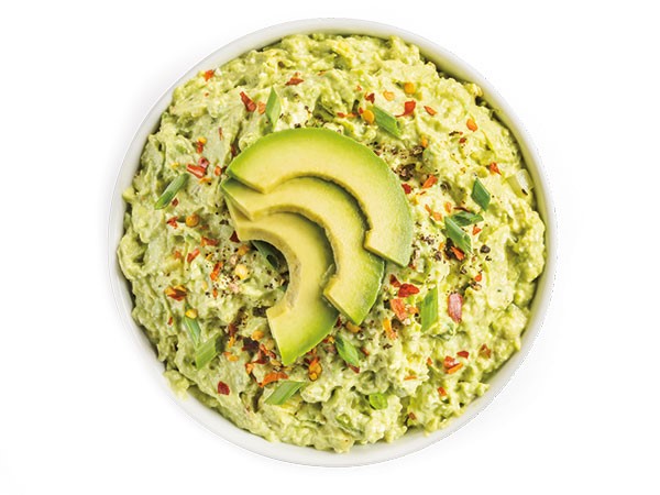 Creamy avocado dip garnished with green onions, avocado slices, and red pepper flakes
