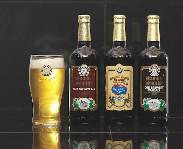 Three craft beer bottles next to beer in pilsner glass