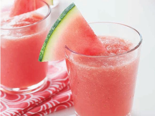 Glass of pink slushie, garnished with a watermelon wedge