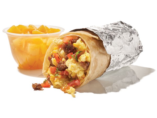 Breakfast burrito wrapped in aluminum foil with a fruit cup