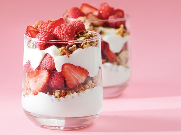 Glasses layered with yogurt, granola and strawberries and raspberries