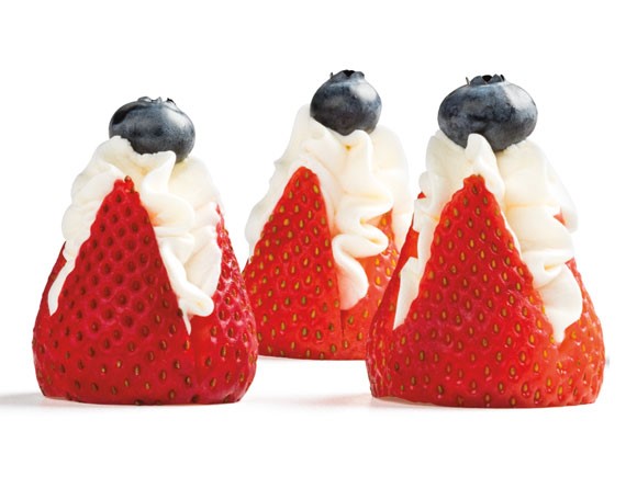 Three strawberries stuffed with whipped topping and garnished with a blueberry