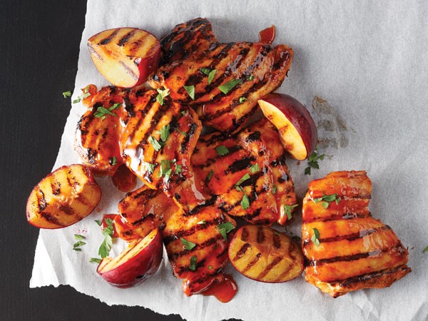 Honey-sriracha grilled chicken thighs served with grilled peaches on parchment paper