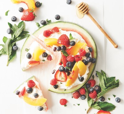 Round watermelon slice topped with yogurt and fresh berries.