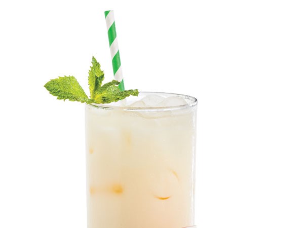 Glass filled with bourbon colada with a green-and-white striped straw