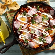Harissa chilaquiles skillet topped with sour cream, cotija cheese and thinly sliced radishes
