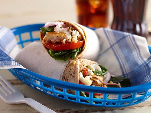 Two chicken gyro wraps in a blue basket with a blue-and-white napkin