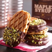 Salted caramel buttercream sandwiched between two waffle crisp cookies and partially dipped in dark chocolate and covered in chopped pistachios
