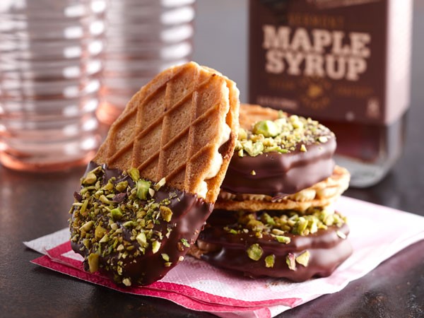 Salted caramel buttercream sandwiched between two waffle crisp cookies and partially dipped in dark chocolate and covered in chopped pistachios